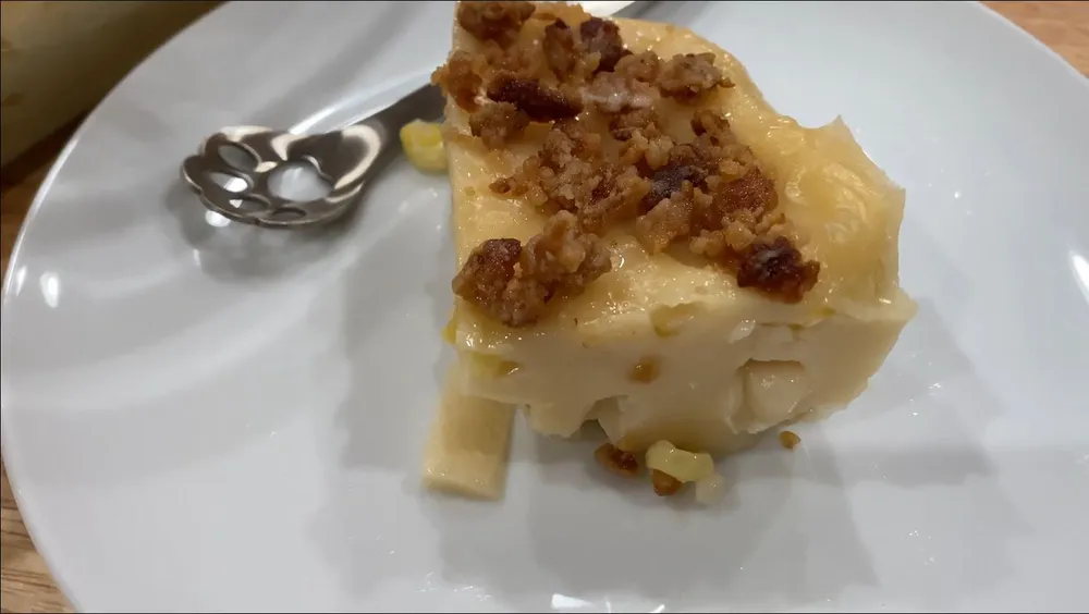 Maja Blanca slice on a plate with small spoon and latik on top