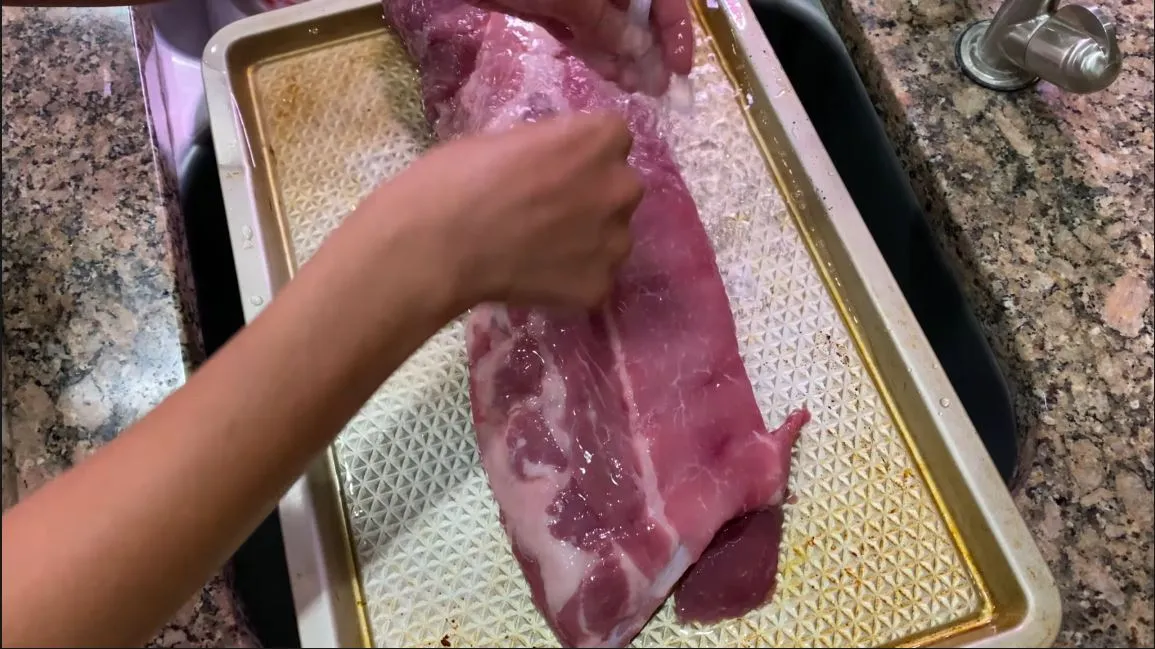 Cleaning baby back ribs with water before applying dry rub in sink