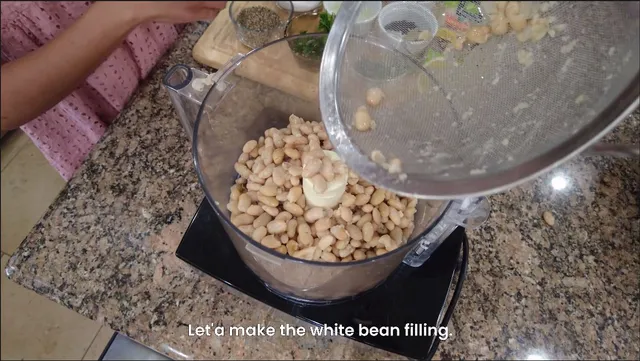 white beans being placed in food processor for white bean ravioli recipe
