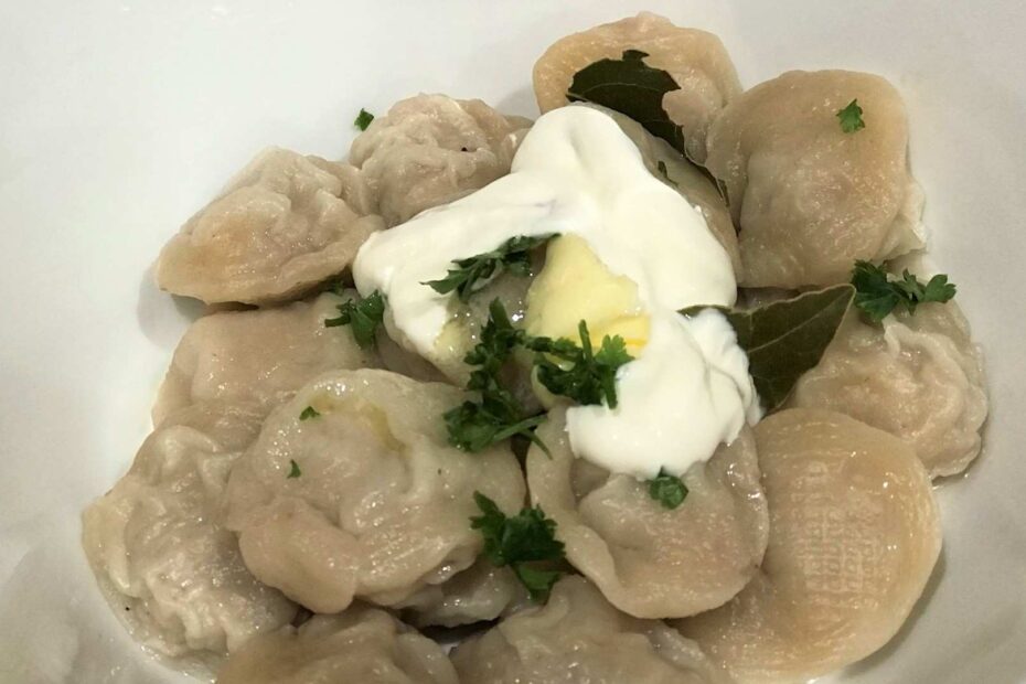 Homemade cooked pelmeni with sour cream in a bowl