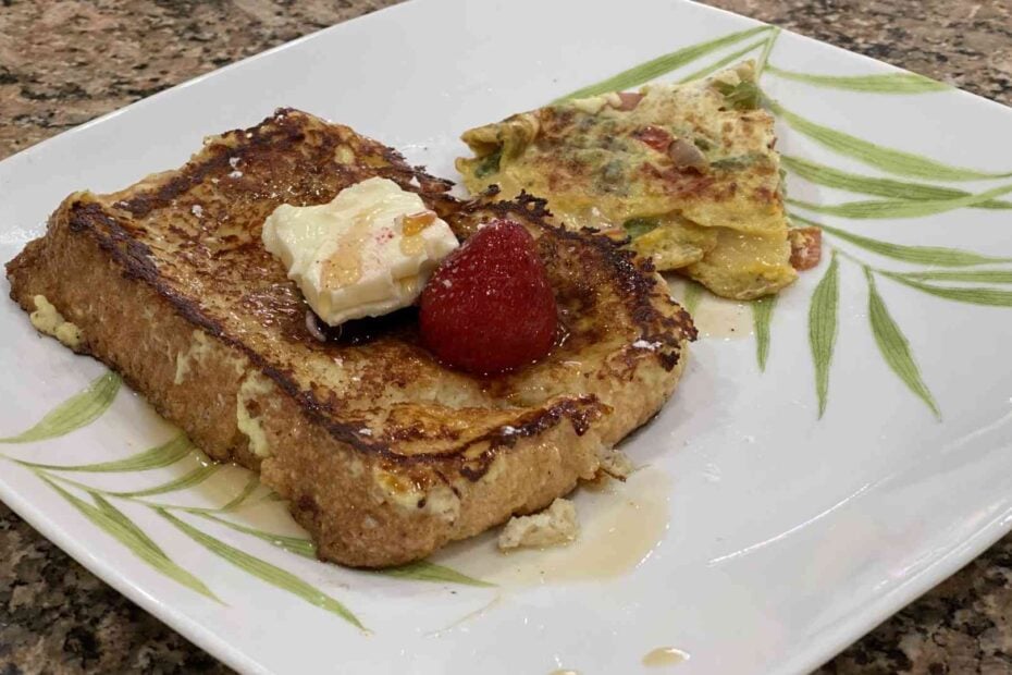 homemade french toast with butter, fruit, maple syrup and omelet on the side