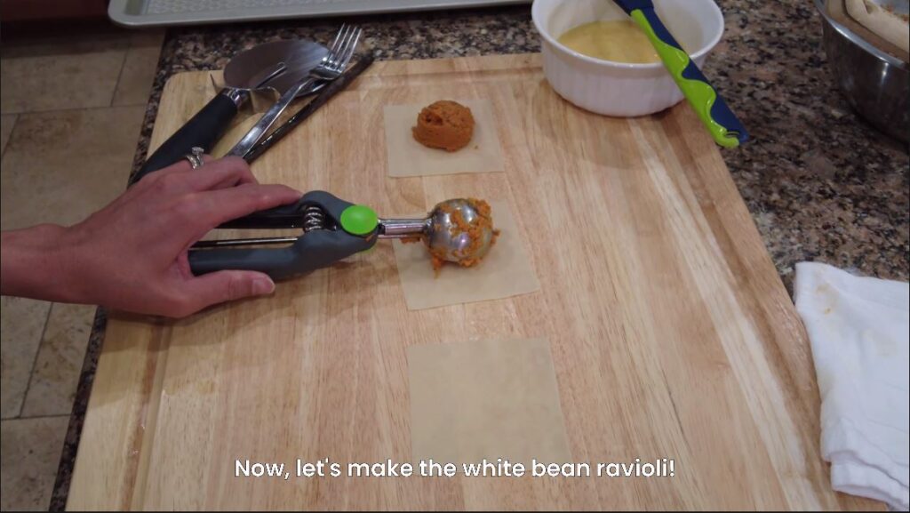 White bean and tomato mix being placed on won ton wrapper for white bean ravioli recipe
