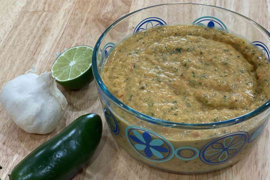 mango salsa in a bowl with jalapeno, lime, and garlic next to bowl