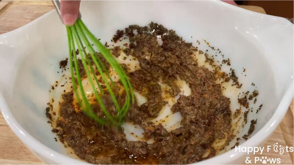 wisking sun dried tomato vinaigrette in a glass bowl