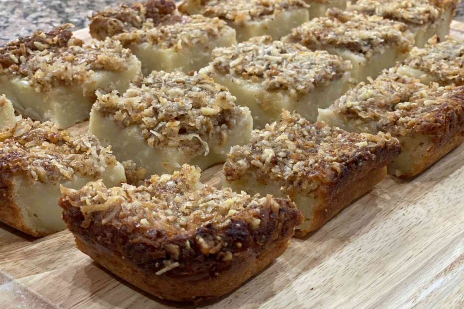 Hawaiian Butter Mochi cut into squares on a wooden cutting board