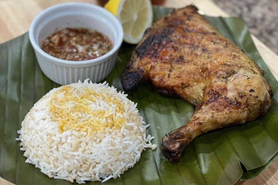 Filipino chicken inasal with rice on a banana leaf with sauce