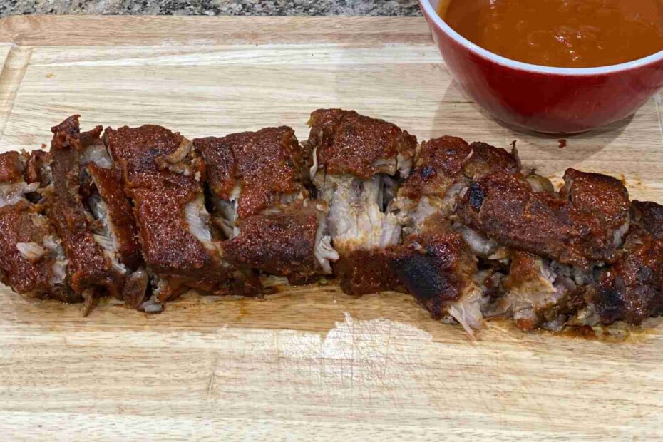 Hawaiian Baby Back Ribs on a cutting board with a bowl of coconut guava sauce