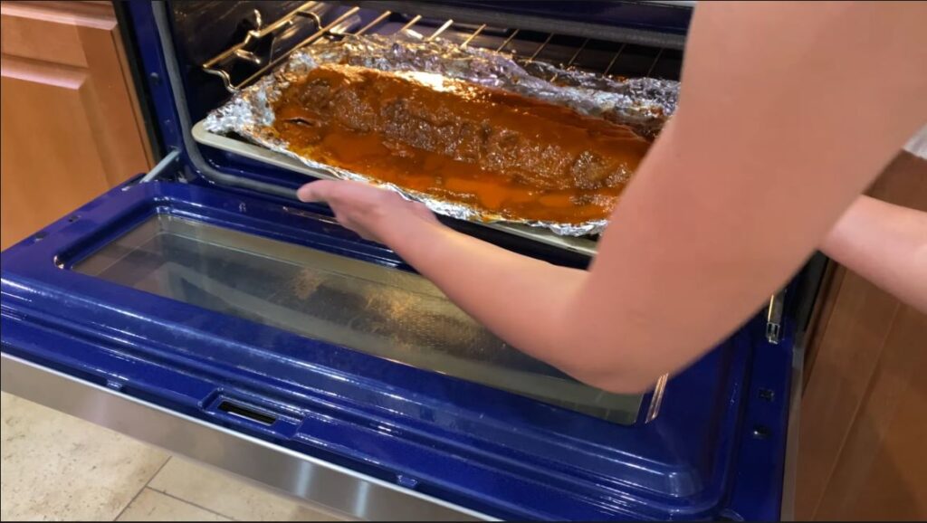 Adding baby back ribs to oven with coconut rub guava glaze