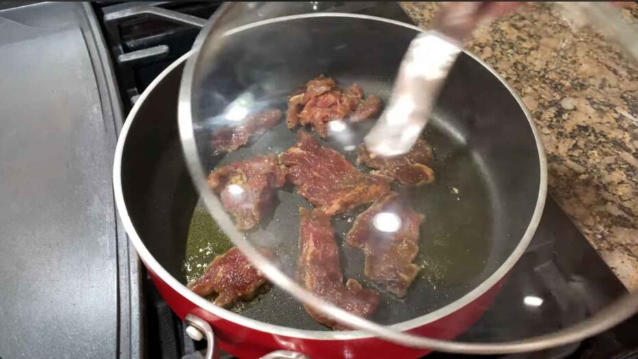Cooking the marinaded beef tapa with a little oil in a saucepan.